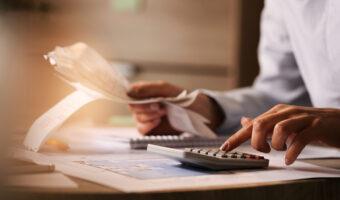 Close-up of business accountant using calculator while working i