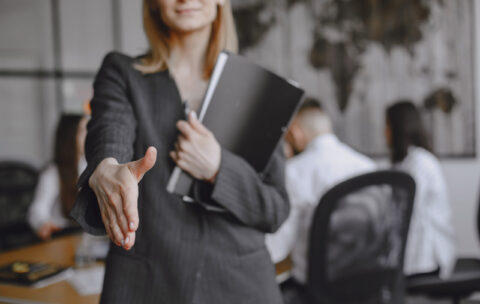 Woman in a suit holds a folder.