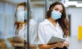 Portrait of young business woman in protective face mask an office building hallway.
