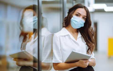 Portrait of young business woman in protective face mask an office building hallway.