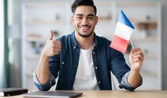 Smiling guy with flag of France and showing thumb up