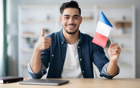 Smiling guy with flag of France and showing thumb up