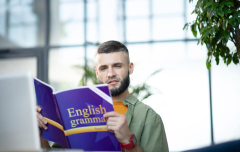 Bearded young businessman studying English grammar