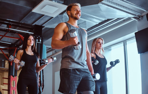 Group of people exercising with dumbbells in a fitness club or gym.