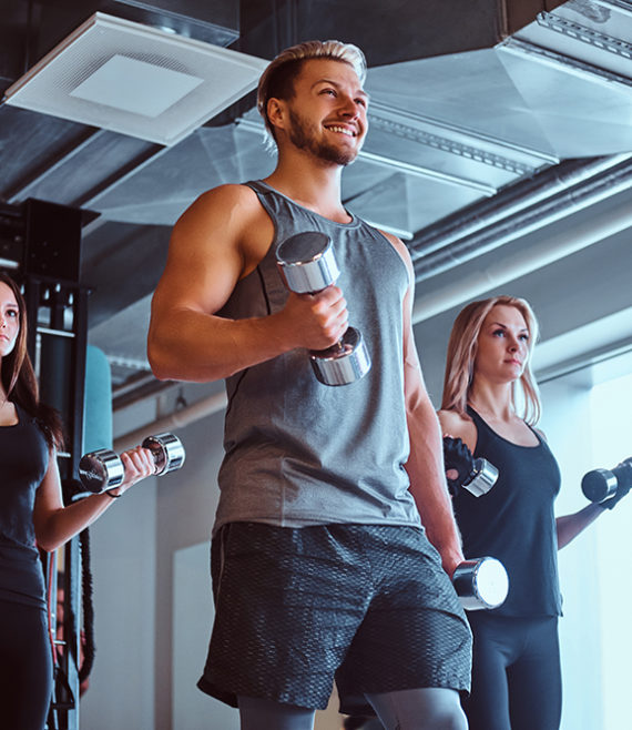 Group of people exercising with dumbbells in a fitness club or gym.