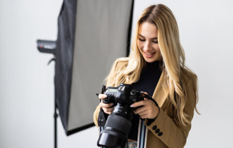 Young beautiful female posing for a photo shoot in a studio, a photographer is shooting with a digital camera