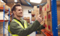 Male Worker Wearing Inside Warehouse Scanning Stock Barcode On S