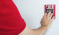 Man is reaching his hand to push fire alarm hand station