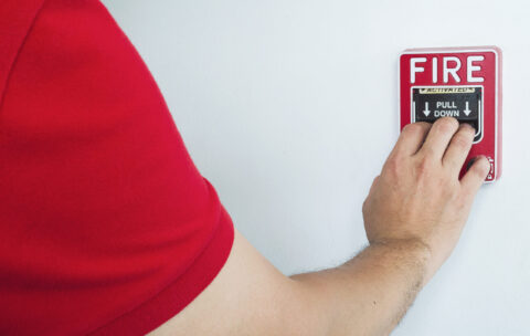 Man is reaching his hand to push fire alarm hand station