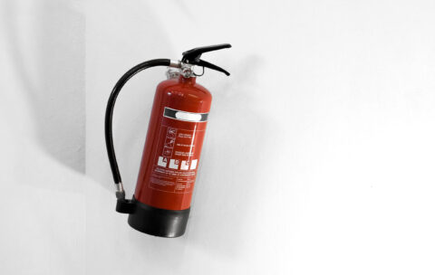 Red fire extinguisher on a white wall