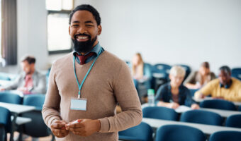 Happy black adult education teacher in lecture hall looking at camera.
