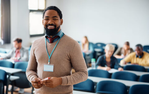 Happy black adult education teacher in lecture hall looking at camera.