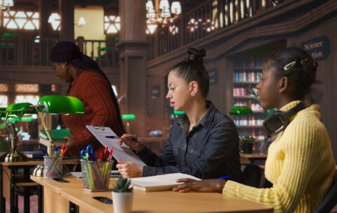 Portrait of cute young schoolgirl entering the library to study in peace