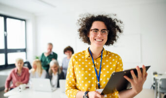 Portrait of teacher with seniors attending computer and technology education class.