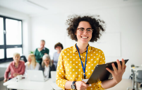 Portrait of teacher with seniors attending computer and technology education class.