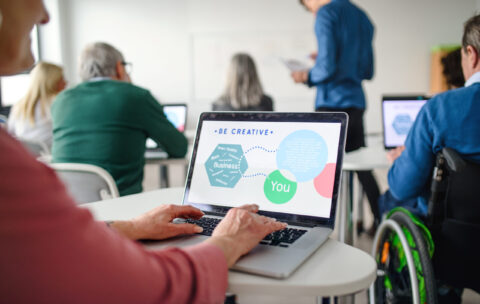 Rear view of senior people attending computer and technology education class.