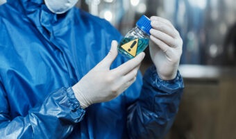 Close up of worker holding blue liquid activator at chemical plant