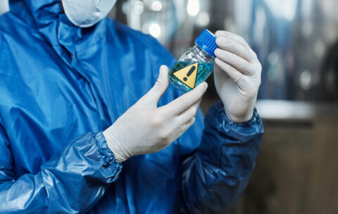Close up of worker holding blue liquid activator at chemical plant