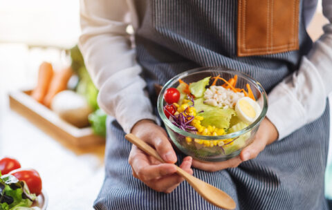 Closeup image of a female chef cooking and holding a bowl of fre