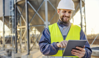 An industry worker using tablet for checking on supply in silos.
