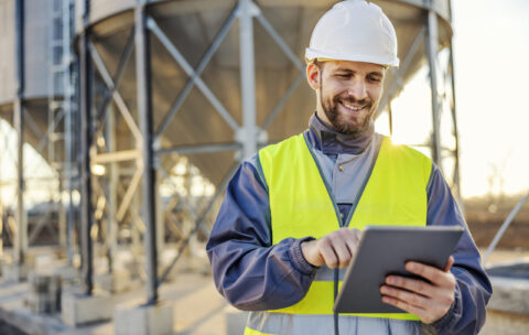 An industry worker using tablet for checking on supply in silos.