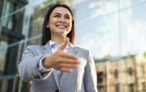 low-angle-smiley-businesswoman-giving-hand-handshake-outdoors