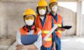 colleagues-with-safety-equipment-working-with-blueprints