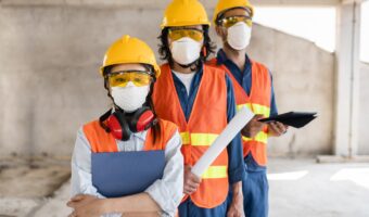 colleagues-with-safety-equipment-working-with-blueprints