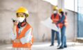 colleagues-with-safety-equipment-working-with-blueprints