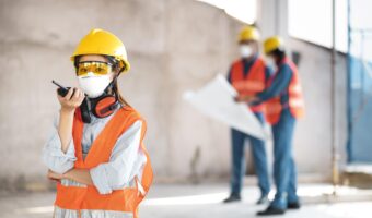colleagues-with-safety-equipment-working-with-blueprints