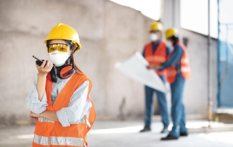 colleagues-with-safety-equipment-working-with-blueprints