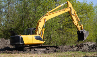 Excavator before working day of digging against forest