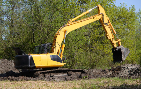 Excavator before working day of digging against forest