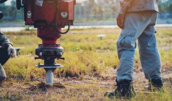technician installing ground screw for mounting structure of solar panel at solar farm