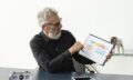 older-man-home-showing-graph-notepad-with-tablet-desk (1)
